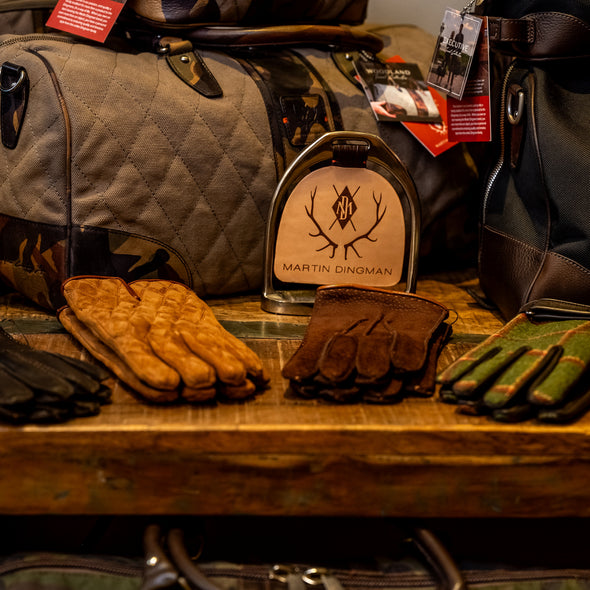 Gloves and bags on a wooden table with a brand sign in the background