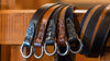 5 variants of Harrison O-Ring Leather Belts wrapped around a banister; walnut and whiskey calf leather belts, with navy, tobacco and walnut suede leather belts.