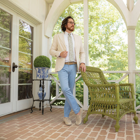 Man standing on a porch with a green chair and potted plant